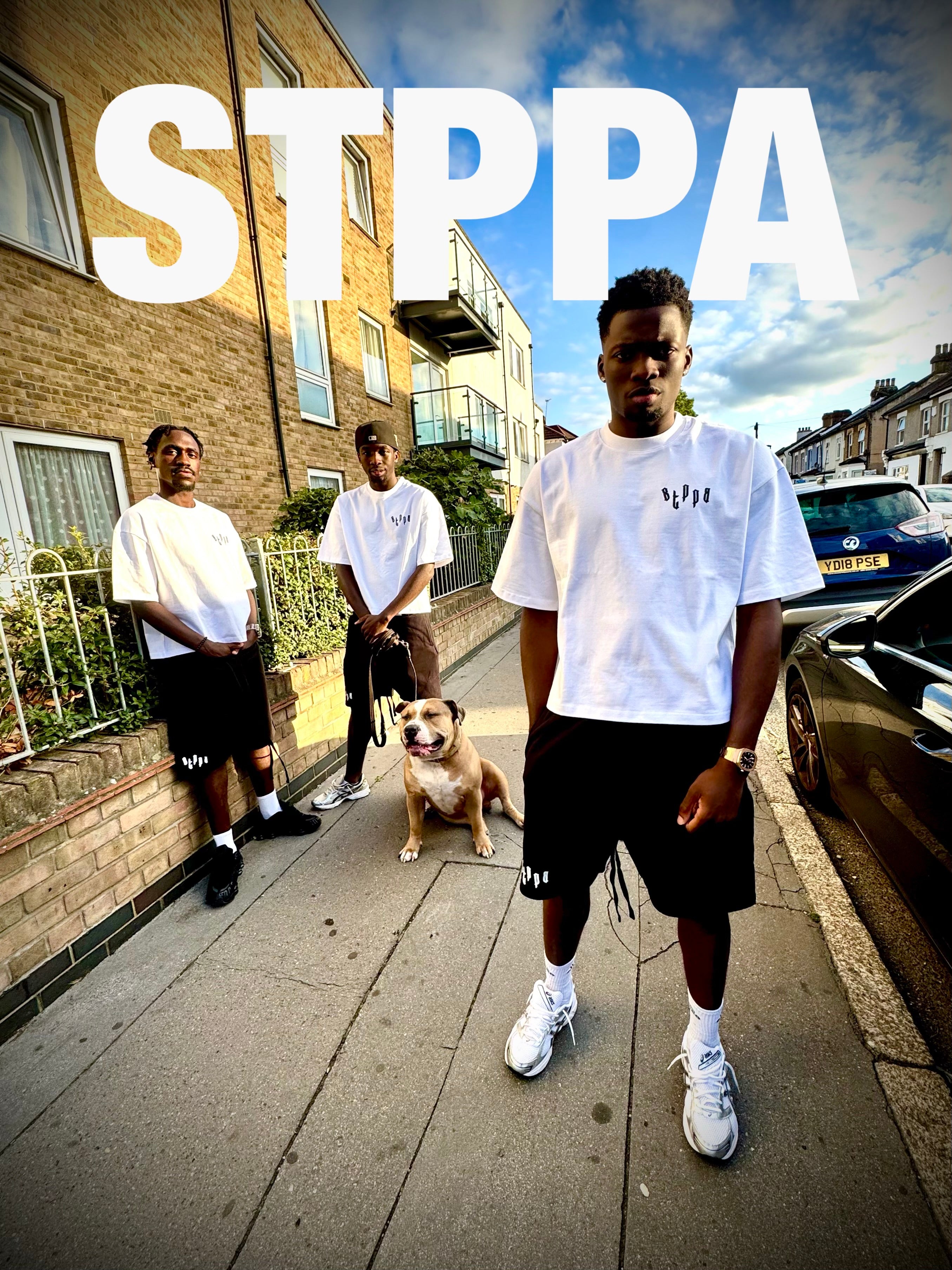Three men standing on a street with a dog, wearing white t-shirts and black shorts, with 'STPPA' text overlay.
